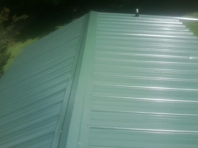 New green metal panels meeting at the ridge of a roof — Flat Roof Repair work by our crew in Bethel Island