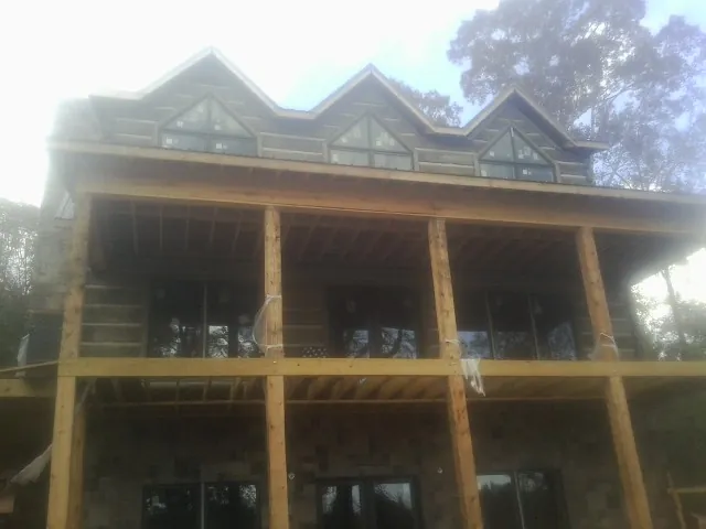 Dormers and porch framing on a large log home under construction — Roof Coating work by our crew in Bethel Island