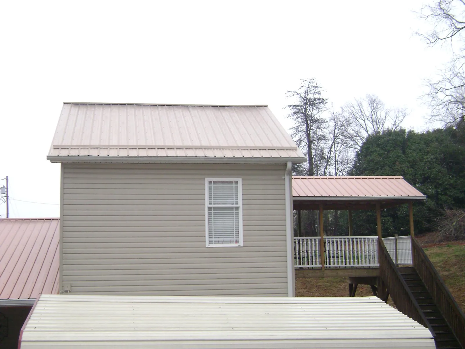 Tan metal roofs on a two story addition and attached porch, from a Roof Replacement job in Bethel Island