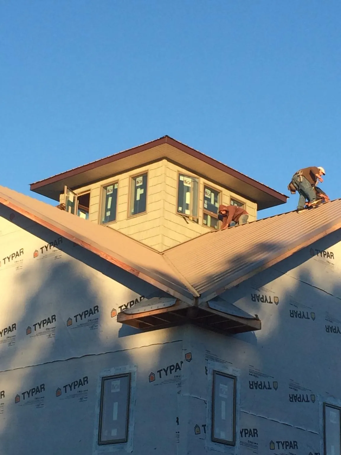 Roofers working around a rooftop cupola on a new metal roof at sunset — Roof Waterproofing in Bethel Island by Roofing Brothers